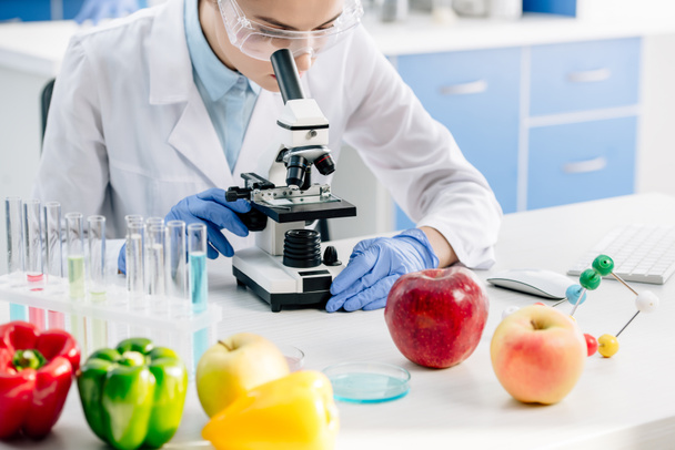 cropped view of molecular nutritionist using microscope and sitting at table  - Photo, Image