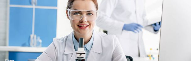panoramic shot of smiling molecular nutritionist looking at camera  - Photo, Image