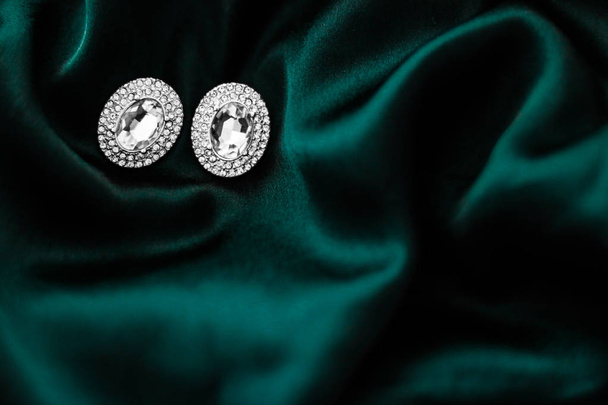 Роскошные бриллиантовые серьги на темно-изумрудно-зеленом шелке, праздничный глэм
 - Фото, изображение