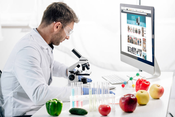 KYIV, UKRAINE - OCTOBER 4, 2019: side view of molecular nutritionist using computer with amazon website  - Photo, image