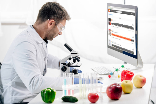 KYIV, UKRAINE - OCTOBER 4, 2019: side view of molecular nutritionist using computer with soundcloud website  - Photo, image
