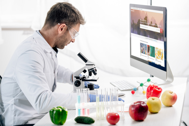 KYIV, UKRAINE - OCTOBER 4, 2019: side view of molecular nutritionist using computer with shutterstock website  - Photo, image