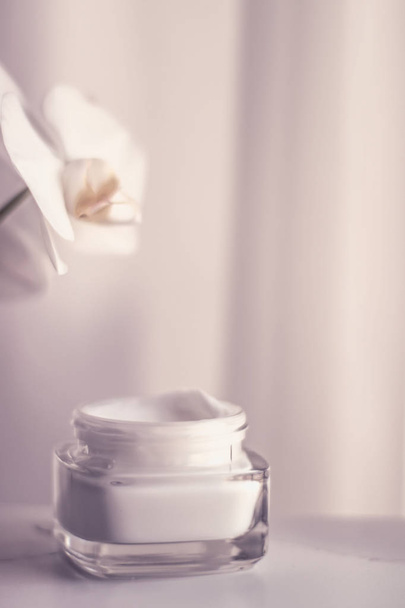 Face cream moisturizer jar and orchid flower, moisturizing skin  - Фото, изображение