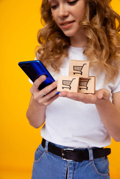 Online vásárlás koncepció. Nő mobiltelefonnal és bevásárló kosárral. - Fotó, kép
