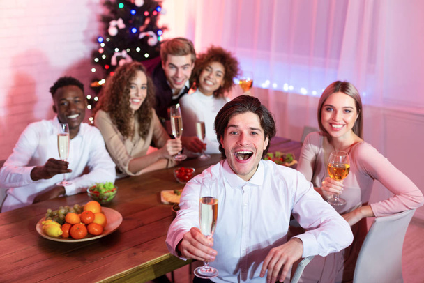 Vrienden Holding Bril zitten aan tafel met Kerstmis Home Party - Foto, afbeelding