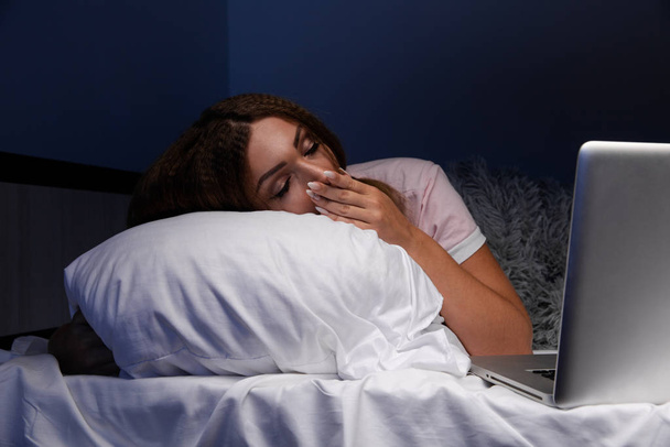 Awake young woman at night in the bed working laptop. - Foto, Imagen