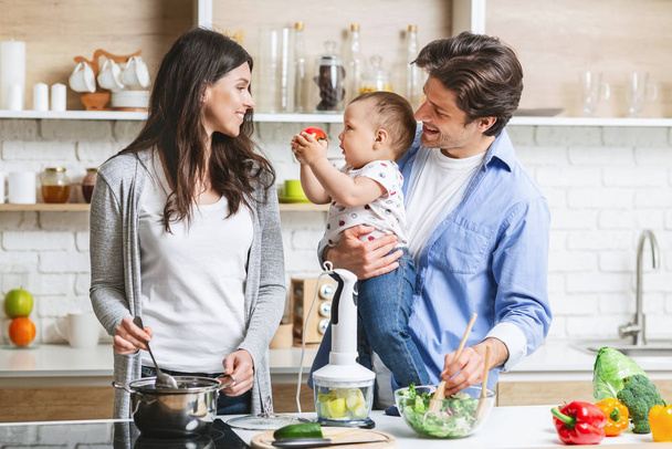 Веселые родители готовят обед с маленьким сыном на кухне
 - Фото, изображение
