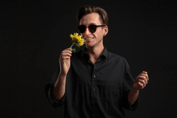 Przystojny mężczyzna trzyma piękny żółty kwiat, aby dać go ukochanemu. - Zdjęcie, obraz