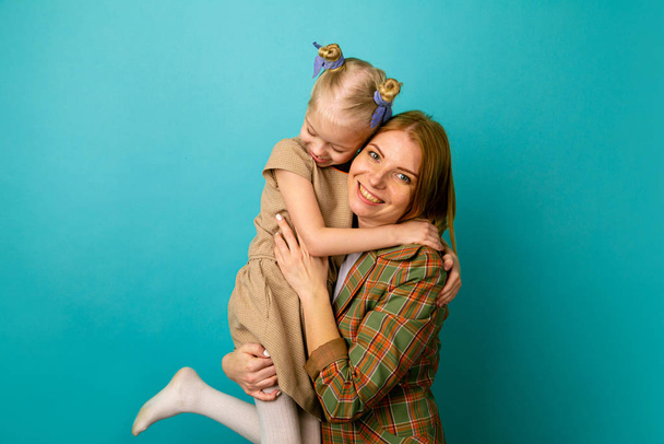 Mother and little daughter in a studio isolated hugs and smiling. - Photo, Image