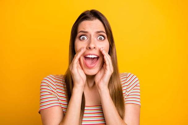 Closeup photo of terrified lady holding hands near mouth screaming loudly see street wanted bandit wear casual striped t-shirt isolated yellow color background - 写真・画像