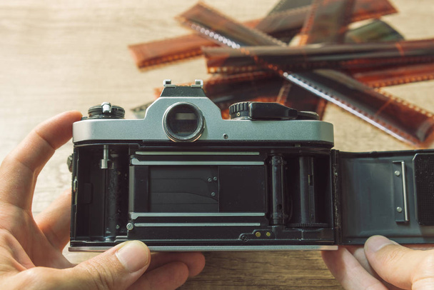 The film looks of the vintage camera in hand with a blurred film strip background. - Photo, Image