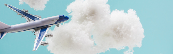 toy plane flying among white fluffy clouds made of cotton wool isolated on blue, panoramic shot - Фото, зображення