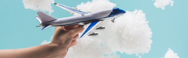 vista recortada de la mujer jugando con el avión de juguete entre las nubes esponjosas blancas hechas de algodón aislado en azul, tiro panorámico
 - Foto, Imagen