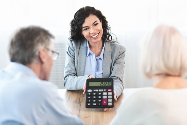 Asesor financiero latino mostrando calculadora a pareja de ancianos
 - Foto, Imagen