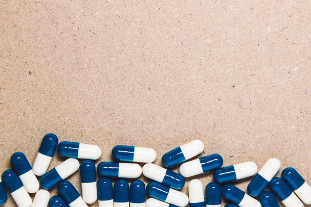 White and blue drug capsules with empty copy space on a wooden board background. - Фото, зображення