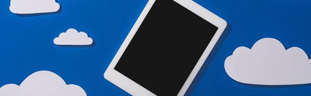 vista superior do papel branco cortar nuvens e tablet digital em fundo azul, tiro panorâmico
 - Foto, Imagem