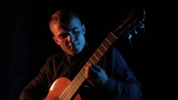 hudebník virtuos hraje klasickou akustickou kytaru na černém pozadí, detail obličeje, izolované - Záběry, video