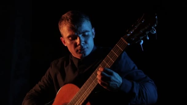 virtuoso músico toca la guitarra acústica clásica sobre un fondo negro, primer plano de la cara, aislado
 - Imágenes, Vídeo