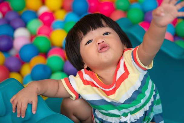 Šťastná asijská dívka (jeden a půl roku) hraje malé barevné kuličky v kulečníku. Koncept hraní je nejlepší učení pro děti. - Fotografie, Obrázek