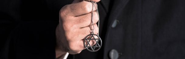 tiro panorâmico de homem judeu que mantém estrela de colar de david
  - Foto, Imagem