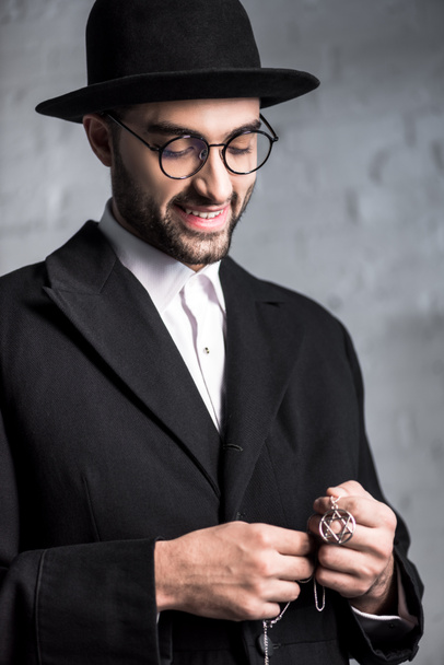 jóképű és mosolygós zsidó férfi kezében csillag David nyaklánc  - Fotó, kép