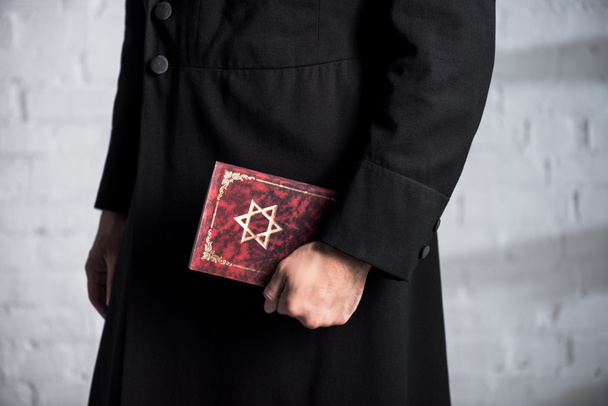 cropped view of young jewish man holding tanakh  - Fotó, kép