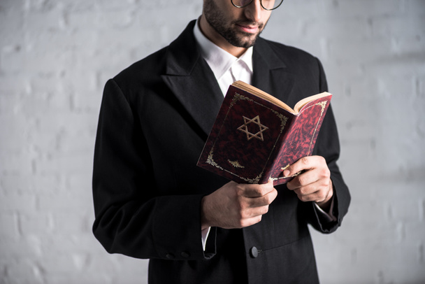 cropped view of young jewish man reading tanakh  - Zdjęcie, obraz