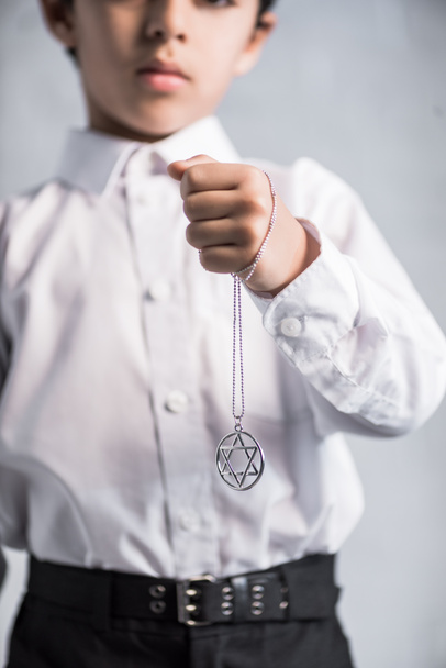 cropped view of jewish boy in shirt holding star of david necklace  - 写真・画像