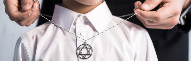 panoramic shot of jewish father wearing star of david necklace on son   - Photo, Image