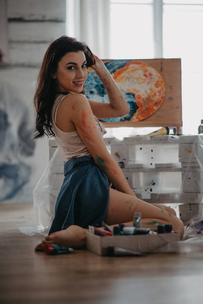 Художник сидить на підлозі в художній майстерні в творчому безладі
. - Фото, зображення
