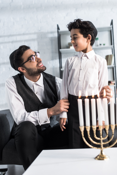 smiling jewish father looking at cute son in apartment  - Foto, afbeelding