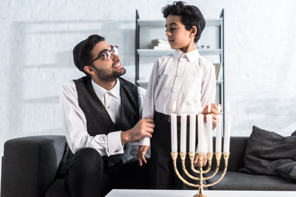 smiling jewish father looking at cute son in apartment  - 写真・画像
