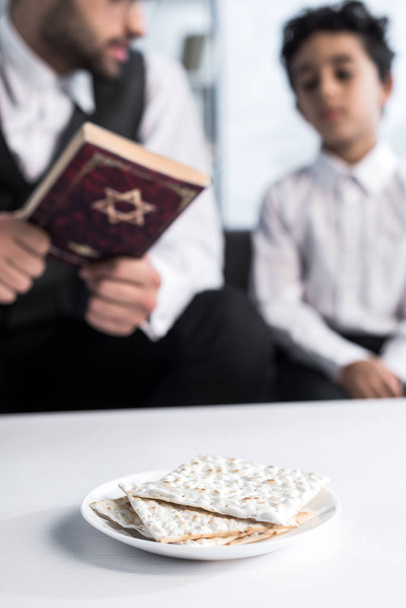 selective focus of matza on plate and jewish father and son on background  - Photo, Image
