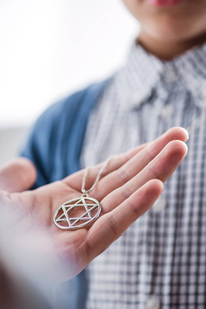 обрезанный вид еврейского отца, держащего звезду ожерелья Дэвида на сыне
  - Фото, изображение