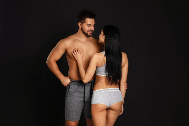 Young couple in grey sportive underwear on black background - Photo, Image