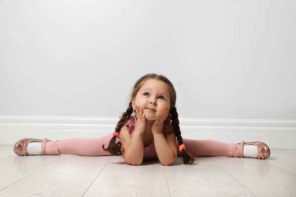 Cute little girl on floor near light grey wall - Foto, imagen