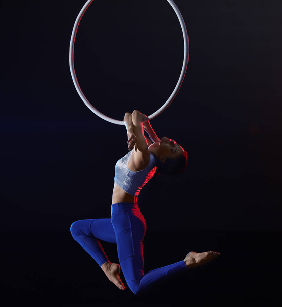 Jeune femme exécutant élément acrobatique sur anneau aérien contre
  - Photo, image