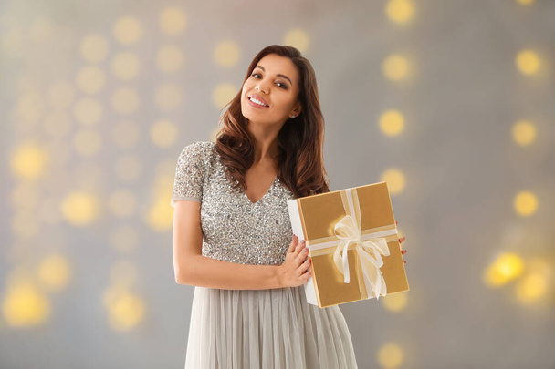 Beautiful woman with Christmas gift on blurred background - Valokuva, kuva