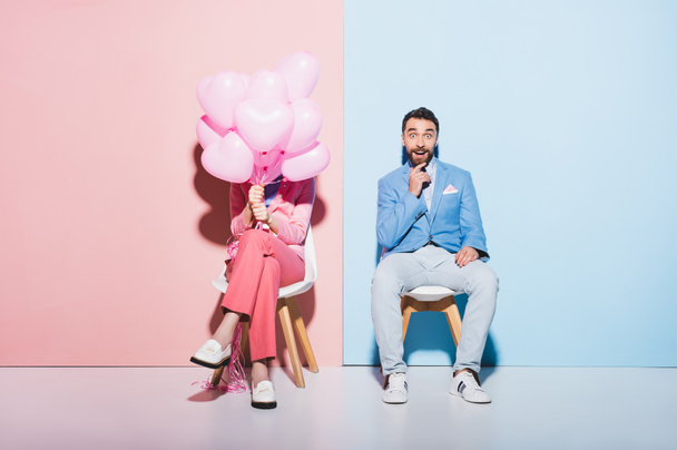 donna in possesso di palloncini e uomo scioccato su sfondo rosa e blu
  - Foto, immagini