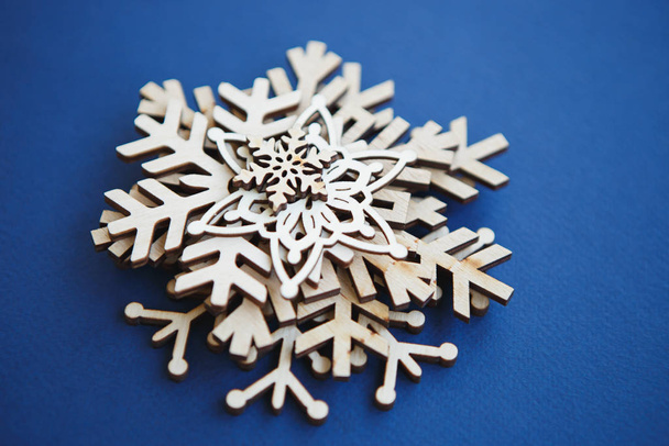 Rustic wooden snowflakes for home decor.Christmas Eve and Happy New Year decorations made from ecological materials.Beautiful hand made rustic crafts in close up,shot on blue background - Foto, Imagen