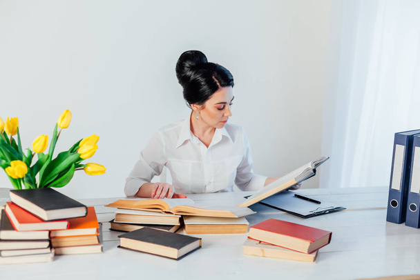 женщины в деловом костюме за столом с книгами
 - Фото, изображение