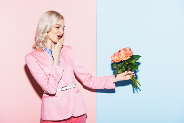 shocked woman holding bouquet on pink and blue background - Photo, Image