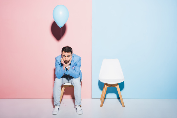 hombre guapo y triste sosteniendo globo sobre fondo azul y rosa
  - Foto, Imagen