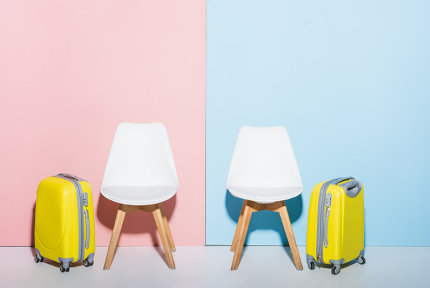 wooden chairs and travel bags on pink and blue background  - Fotoğraf, Görsel