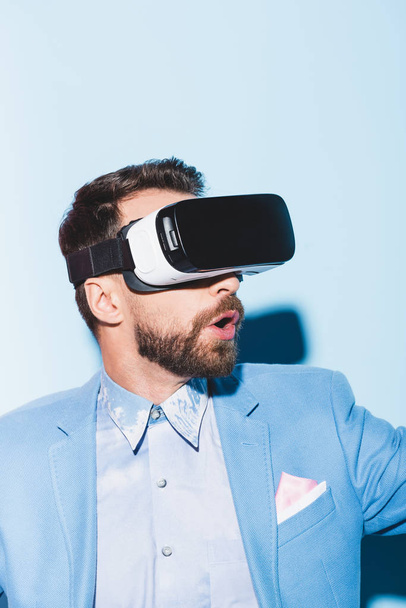 geschokte man in virtual reality headsets op blauwe achtergrond  - Foto, afbeelding