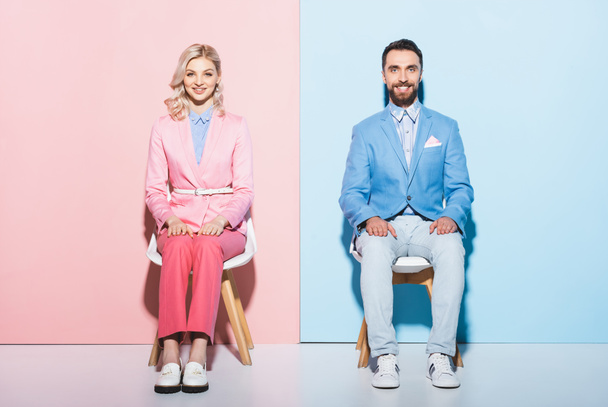 smiling woman and handsome man looking at camera on pink and blue background  - Foto, Imagem
