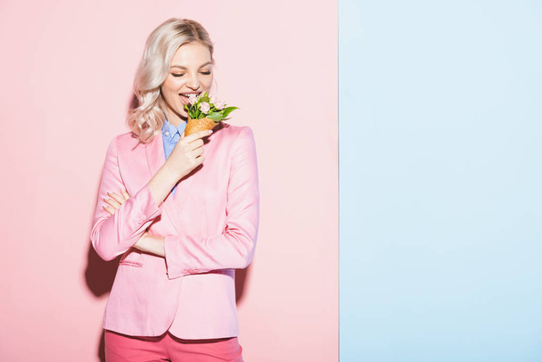 χαμογελαστή γυναίκα τρώει μπουκέτο σε ροζ και μπλε φόντο  - Φωτογραφία, εικόνα