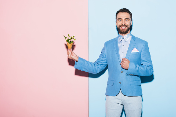smiling man holding bouquet on pink and blue background  - Fotoğraf, Görsel