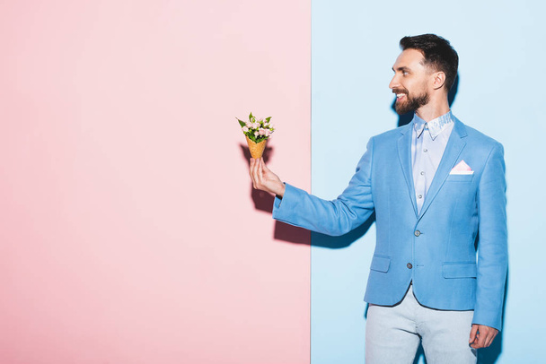 smiling man holding bouquet on pink and blue background  - Photo, Image