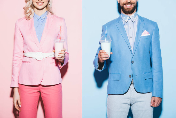 cropped view of smiling woman and man holding cocktails on pink and blue background  - Photo, image